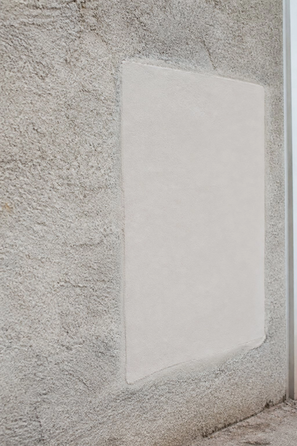 Repaired section of concrete facade showing smooth patch against textured surface